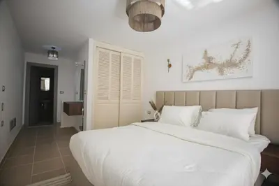 a bedroom with a large white bed and a hallway at Modern Sahl Hasheesh Pool Duplex - Beach & Wi-Fi in Hurghada