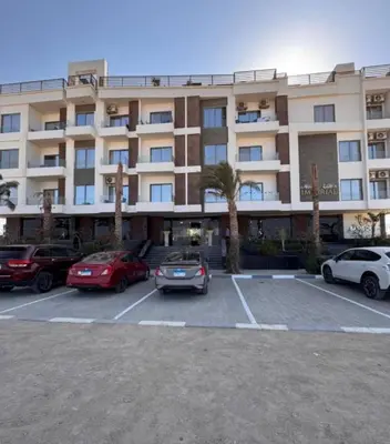 a large building with cars parked in a parking lot at 412atthepavilionimperialHurghada in Hurghada
