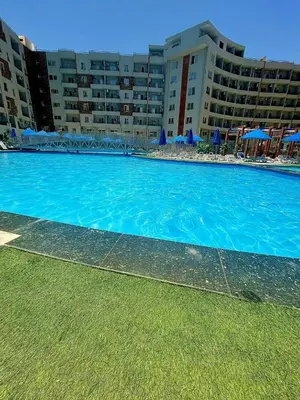 a large blue swimming pool in front of a building at Pearl of Tiba Golden Resort in Hurghada