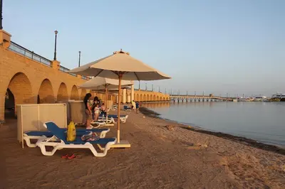 a group of people sitting on a beach with umbrellas at 310 el Andalous Apartment in Hurghada