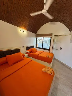 two beds in a room with orange sheets at Nubian Dreams guest house 2 in Aswan