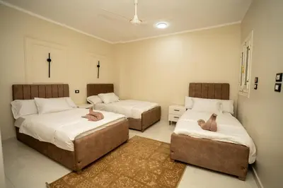 a bedroom with two beds and two ottomans at ElMena House Luxor in Luxor