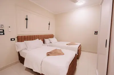 two beds in a hotel room with white walls at ElMena House Luxor in Luxor