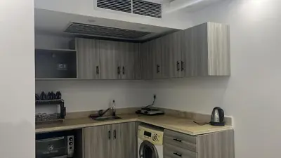 a kitchen with wooden cabinets and a washer and dryer at Fanadir bay in Hurghada