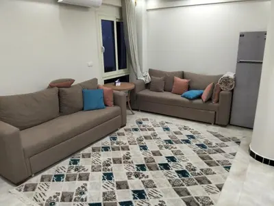 a living room with two couches and a rug at كومباوند البرنسيسه in Hurghada