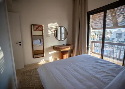 a bedroom with a bed and a mirror and a window at Ancient Sands El Gouna Hurghada in Hurghada