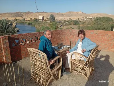 two older people sitting at a table in chairs at Sugar Nubian Guest House Nile Vew in Aswan