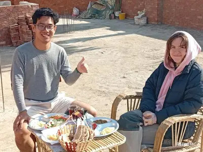 a man and a woman sitting at a table with food at Sugar Nubian Guest House Nile Vew in Aswan