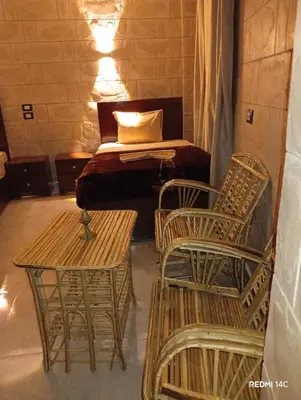 a bedroom with a bed and two chairs and tables at Sugar Nubian Guest House Nile Vew in Aswan