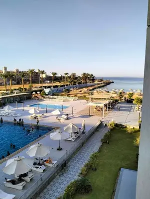 a pool with umbrellas and people in the water at One bedroom Chalet Scandic Resort Hurghada in Hurghada