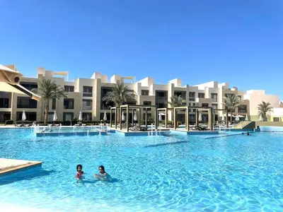 two people swimming in a swimming pool in a resort at Mangrove M1-5B-13 in Banī Ghālib