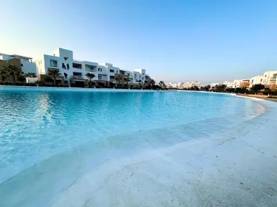 a large pool of blue water with buildings in the background at Comfortable 3BR Apartment in Swan Lake I El Gouna Ground Floor, Garden, Terrace & Lagoon Access in Hurghada