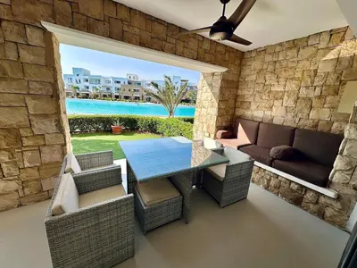 a living room with a table and a couch at Comfortable 3BR Apartment in Swan Lake I El Gouna Ground Floor, Garden, Terrace & Lagoon Access in Hurghada
