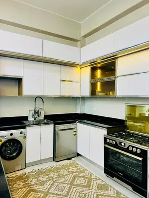 a kitchen with white cabinets and a sink and a dishwasher at Quiet Villa in Luxor