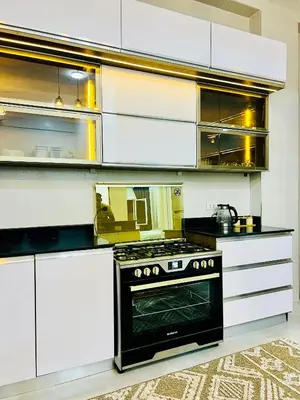 a kitchen with white cabinets and a black oven at Quiet Villa in Luxor