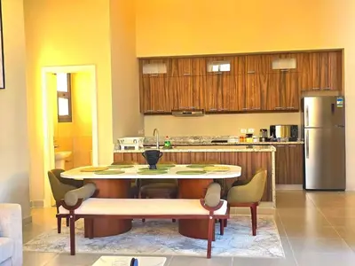 a kitchen with a table with chairs and a refrigerator at El Gouna Cyan the Range 4BDs Villa with private Pool in Hurghada