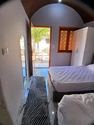a room with two beds and a hallway with a window at ARKN angel Nubian Guest House in Jazīrat al ‘Awwāmīyah