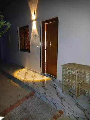 a room with a door and a table and a desk at ARKN angel Nubian Guest House in Jazīrat al ‘Awwāmīyah