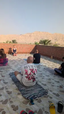 a man sitting on a rug in the desert at Karima house B in Al Aqālitah