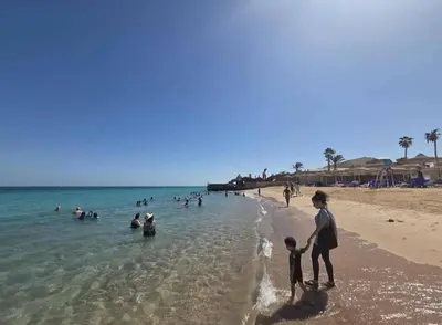 a woman and a child walking on the beach at Juliana Beach Resort Hurghada AG10 in Hurghada