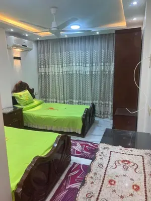 two beds in a room with green sheets and a window at Flat in Nag` el-Ramla
