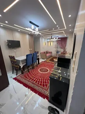a living room with a table and a red rug at Aswan in Nag` el-Ramla
