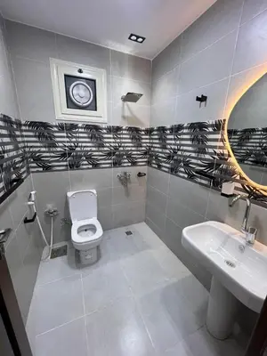 a bathroom with a toilet and a sink and a clock at Aswan in Nag` el-Ramla