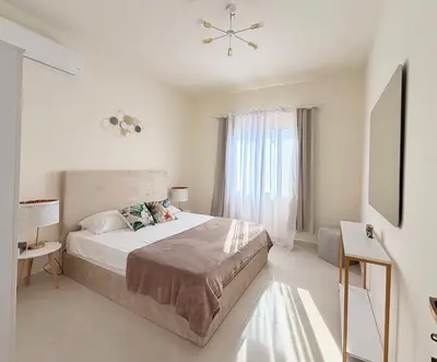 a white bedroom with a bed and a window at Casa Esmeralda in Hurghada