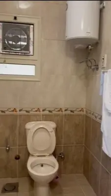 a bathroom with a white toilet and a window at katakitu in Hurghada