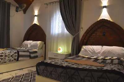 a bedroom with two beds and a window at Isis Magic House in Luxor