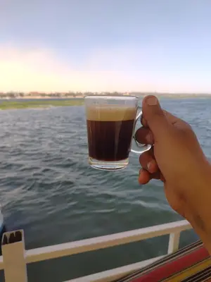 a person holding a glass of beer on a boat at Nile SE Felucca nile cruise private tour in Naj‘ al ‘Amrāb