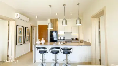 a kitchen with two bar stools and a refrigerator at Ollystays Shedwan 2 BR Pool & lagoon access in Hurghada