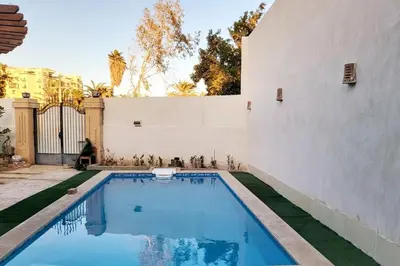 a swimming pool next to a white wall at Luxury Red Sea Villa in Hurghada