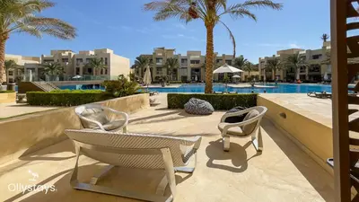 two chairs sitting on a patio near a swimming pool at Ollystays Mangroovy 2 BR Beach and Pool Free access in Hurghada