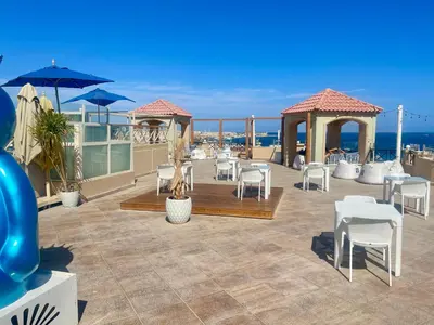 a patio with white chairs and tables and umbrellas at Elegant one bedroom apartment managed by Lilly Homes in Hurghada
