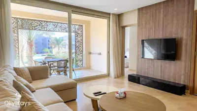 a living room with a couch and a tv on a wall at Ollystays Mangroovy 2 BR Beach and Pool Free access in Hurghada