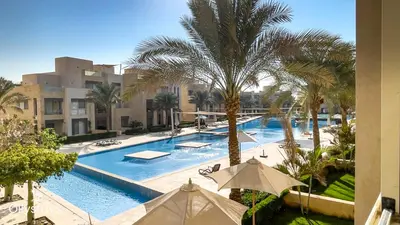 a large swimming pool with palm trees and buildings at Ollystays Mangroovy 2 BR Beach and Pool Free access in Hurghada