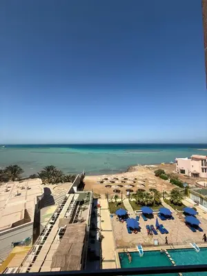 a view of a beach with blue umbrellas and the ocean at Casablanca star hurghada in Hurghada