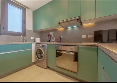 a kitchen with green cabinets and a washing machine at Ollystays Ancient Hill 4BR Villa Private Pool in Hurghada