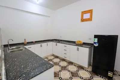 a kitchen with white cabinets and a black refrigerator at Akhet House in Luxor