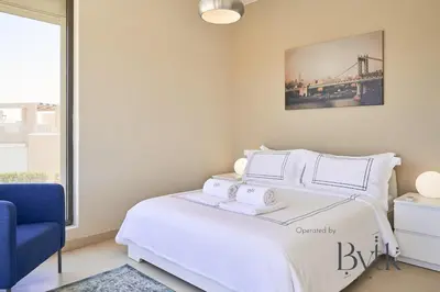 a bedroom with a white bed with a blue chair at BYTK - Casa De Familia in Hurghada