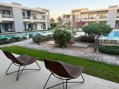 two chairs sitting on a patio next to a swimming pool at The G Cribs Sunlit - El Gouna in El Gouna