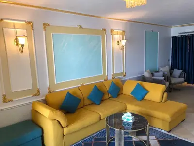 a living room with a yellow couch and blue pillows at New Marina Apartments in Hurghada