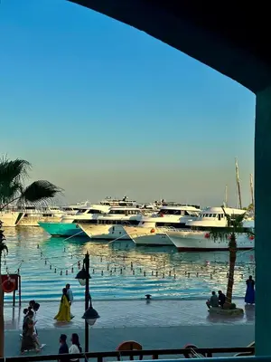 a group of people in a body of water with boats at New Marina Apartments in Hurghada