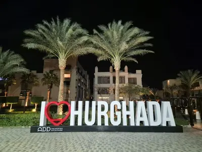 a sign in front of a building with palm trees at Oasya Studio Hurghada in Hurghada