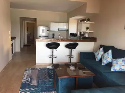 a living room with a blue couch and a kitchen at Sabina Comfort Residence in Hurghada