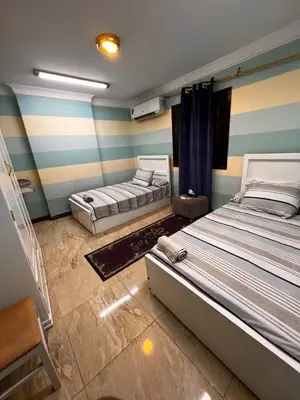two beds in a room with blue and white stripes at Large Nile View apartment 2 Rooms Air-con Downtown in Aswan