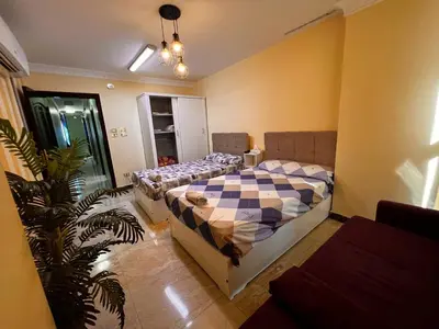 a bedroom with two beds and a plant at Large Nile View apartment 2 Rooms Air-con Downtown in Aswan
