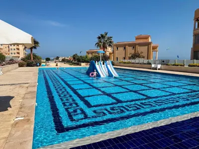 a person is laying on a slide in a swimming pool at Luxurious Apartment in Selena Bay - Private Beach, 5 Pools and Kite Surfing in Hurghada