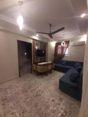 a living room with a blue couch and a table at Horus Heights in Idfu
